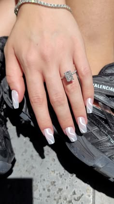 a close up of a person's hand with a ring on her finger and white nail polish