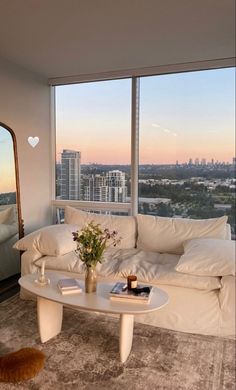 a living room filled with furniture and a large window covered in lots of windows overlooking the city