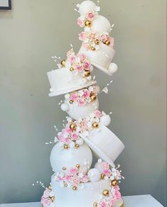 a tall white cake with pink flowers and gold decorations on it's top tier