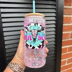 a hand holding a pink tumbler with a cow skull on it and the words maw