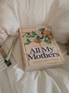 an all my mothers book sitting on top of a bed next to a jar of honey