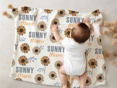 a baby laying on top of a blanket with sunflowers on it's back