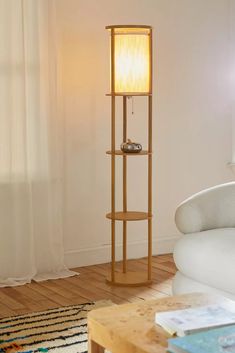 a living room with a white couch and a tall wooden floor lamp in the corner