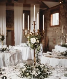 the centerpiece is surrounded by candles and greenery in this elegant wedding reception setting