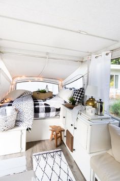 the interior of a camper with white walls and black and white bed linens