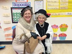 two older women standing next to each other in front of a wall with cupcakes on it