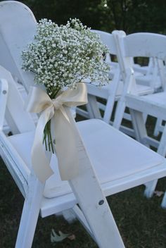 a bouquet of baby's breath sitting on top of a white chair with ribbon