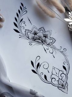 an artistic tattoo design is displayed on a piece of paper with some feathers around it