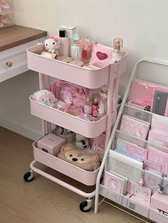 a pink cart filled with lots of items next to a desk