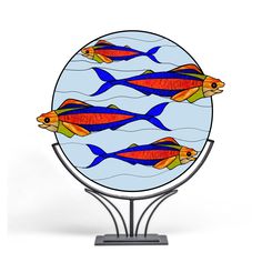 three fish are swimming in the water on a round stained glass display stand with metal legs