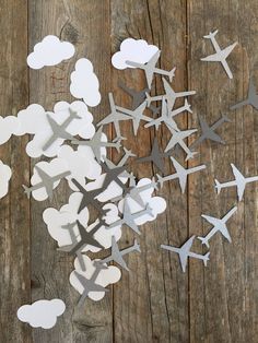 paper airplanes are flying in the air on a wooden surface, with clouds and stars