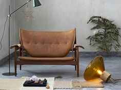 a brown leather couch sitting on top of a floor next to a lamp and rug