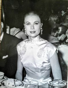 an old black and white photo of a woman sitting at a table with plates on it