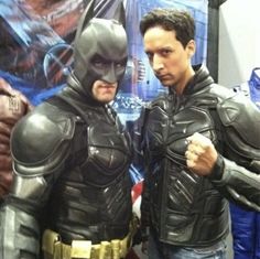 two men dressed in batman costumes standing next to each other