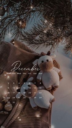 a knitted teddy bear laying on top of a blanket next to a christmas tree