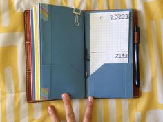 a person's hand is pointing at an open notebook on top of a bed