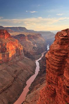 the grand canyon is surrounded by red rocks and cliffs, with a river running between them