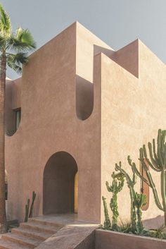 an adobe house with cactus and palm trees