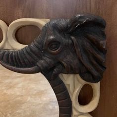 an elephant's head is mounted to the side of a wooden wall mirror with holes in it