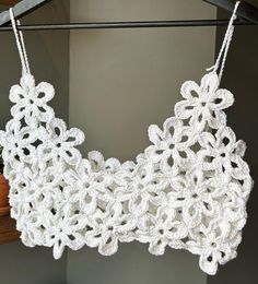 a crocheted bralet hanging on a clothes rack next to a potted plant