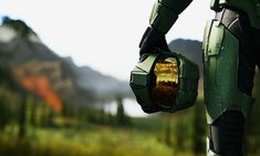 a close up of a robot suit in front of some trees and bushes with mountains in the background