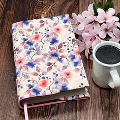 a cup of coffee next to a notebook with flowers on it