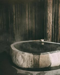 an outdoor hot tub with steam rising from it's sides in front of a wooden wall