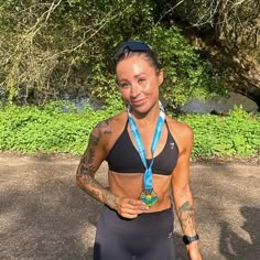 a woman with tattoos on her chest and wearing a black sports bra holding a medal