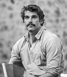 black and white photograph of a man with a moustache sitting on a chair