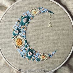 a close up of a embroidery on a hoop with flowers in the shape of a crescent