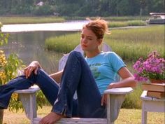 a woman sitting in a chair with her feet up on the ground next to flowers