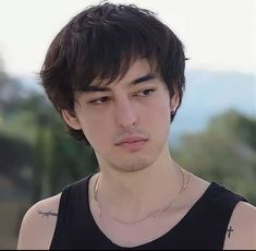 a close up of a person wearing a black tank top with tattoos on his chest