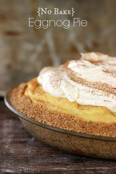 an eggnog pie with whipped cream on top in a glass dish sitting on a wooden table