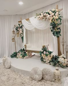 an elaborately decorated stage with flowers and greenery on it, in front of white drapes