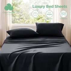 a bed with black sheets and pillows in front of a window that reads luxury bedsheets