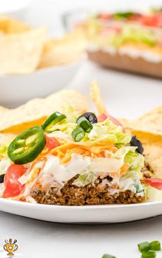 a white plate topped with a taco salad sandwich and tortilla chips next to it