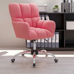 a pink office chair sitting in front of a book shelf with books on it's sides