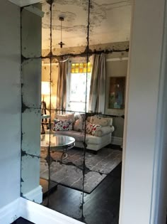 the reflection of a living room in a mirrored door frame is seen through an open doorway