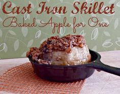 a cast iron skillet with baked apple for one in front of a green sign