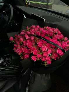 a bunch of pink roses sitting in the center console of a car