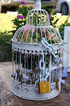 a white birdcage filled with lots of flowers on top of a wooden table