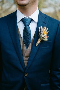 a man wearing a suit and tie with a boutonniere on his lapel