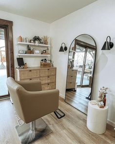 a chair and mirror in a room with wood flooring, white walls and wooden floors