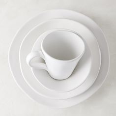 a white cup and saucer sitting on top of each other with plates around it