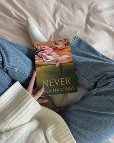 a person laying on top of a bed holding a book