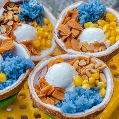 three coconuts filled with cereal and yogurt are on a yellow plastic tray