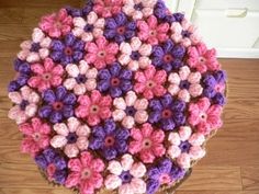 there is a crocheted table top made out of pink, purple and white flowers