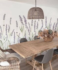 a dining room table and chairs with flowers painted on the wall behind it, along with wicker lampshades