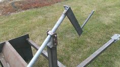 a metal pole with two bars attached to it in the grass next to a field