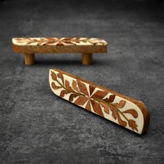 two pieces of wood with designs on them sitting on the ground next to each other